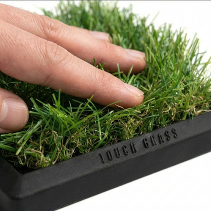 Hand touching artificial grass with 'Touch Grass' branding